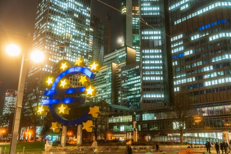 Night view of the iconic Euro sculpture in Frankfurt's bustling financial district.